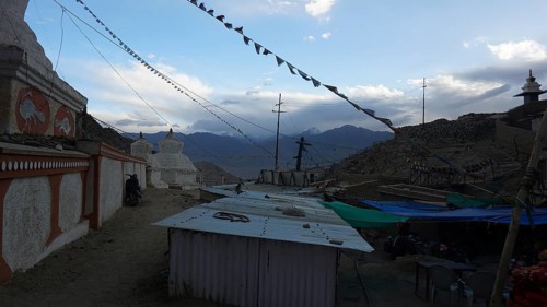 Monastery structures under a blue sky decorated with prayer flags, outskirts of Leh, Ladakh,