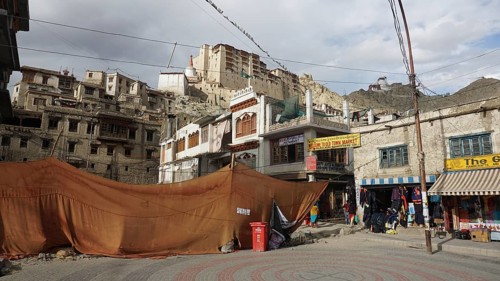Leh Palace and historic buildings with market stalls and tents against a mountainous backdrop in