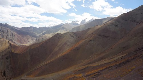 Wide valley surrounded by majestic mountains under bright skies, trekking at Stok La Pass in