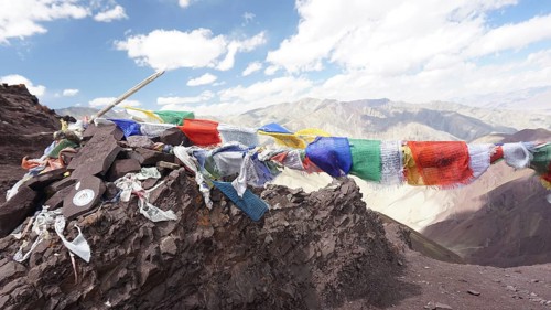 Colourful prayer flags flying over a rocky mountain landscape, trekking at Stok La Pass in Ladakh,