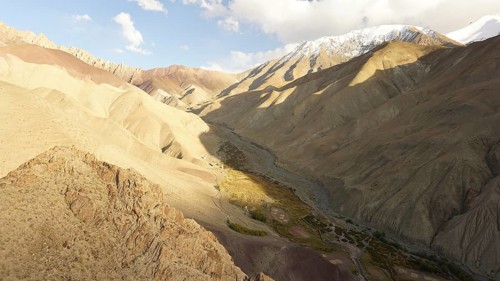Spectacular panorama of a sunny valley crossed by barren mountains, illuminated by dramatic