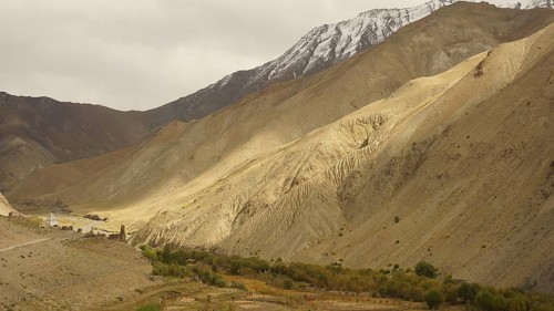 Wide valley with dramatic, barren mountain landscapes under cloudy sky, trekking in Ladakh,