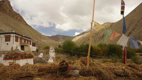 Mountain boot, hiking boots next to prayer flags against mountainous landscape with turbulent