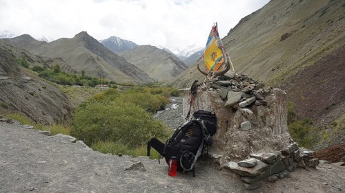 Place of worship with colorful flags and backpack in a mountainous landscape, break on a trekking