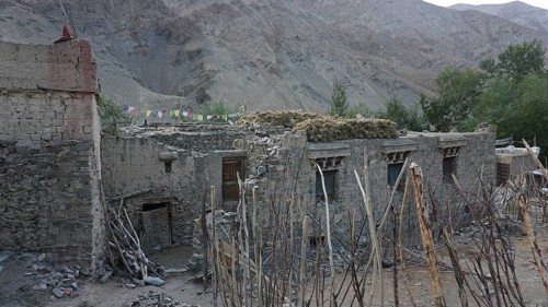 Old stone buildings in a village against a mountainous backdrop, yak (bos mutus) dung lying on the