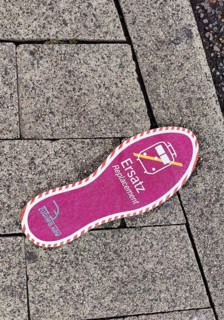 Purple footprint as a signpost on the pavement for rail replacement services, abbreviated SEV, Zug