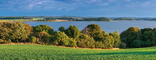 View over green fields and lagoon landscape to Granitz with the hunting lodge, Mönchgut nature
