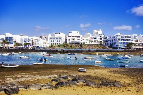 Numerous boats in the Charco de San Ginés lagoon, surrounded by white buildings on the shore,