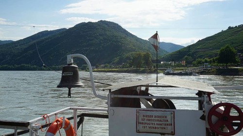 Ferry view of the Danube with flag and green mountains, long-distance cycle path, Danube cycle