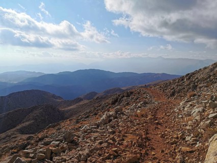 Rocky mountain trail with views of surrounding mountains and clouds, climbing Tahtali Dagi, Lycia,