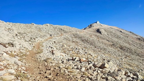 A trail snakes over a rocky mountainside up to the summit of Tahtali with clear skies, climbing