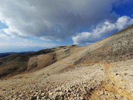 Open mountain trail on Tahtali Dagi under a partly cloudy sky with a wide view, climbing Tahtali