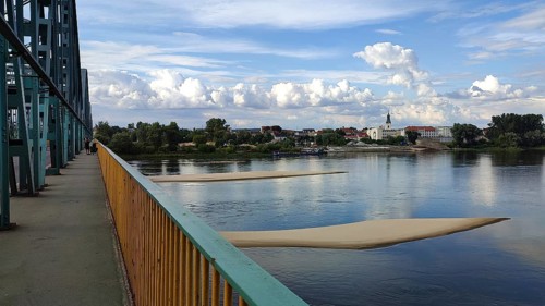 River landscape with two sandbanks in the Vistula with metal bridge, clouds and view of Torun city,