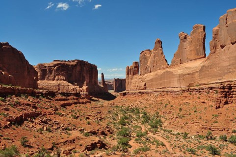 A wide valley with imposing sandstone cliffs, called Wall Street, under a bright blue sky, Arches