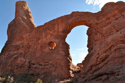 Turret Arch, an impressive sandstone rock arch under a clear blue sky, formed by natural erosion,