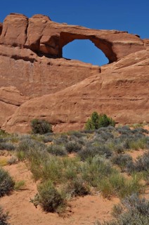 Skyline Arch, a distinctive rock arch in the desert with sparse vegetation, Arches National Park,