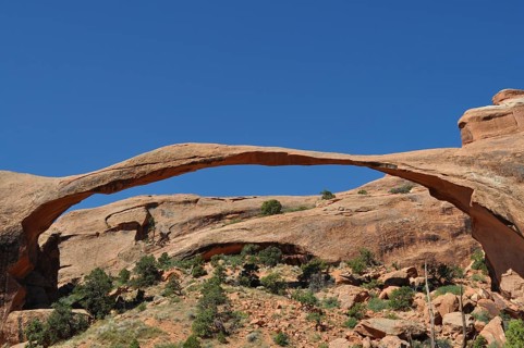 Landscape Arch, an impressive natural stone bridge against bright blue sky, Arches National Park,
