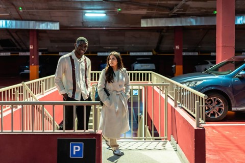 Diverse interracial couple walking up concrete stairs in an urban parking garage, smiling and