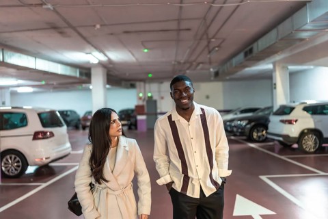 Young interracial couple walking and smiling together in an underground parking garage, looking