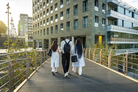 Diverse business colleagues are walking away on an outdoor bridge, heading towards modern corporate