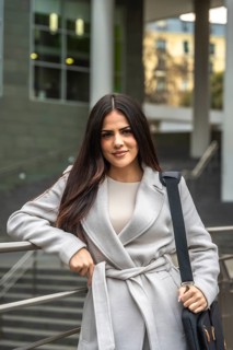 Businesswoman posing with confidence, holding her laptop bag and leaning on a railing, portraying
