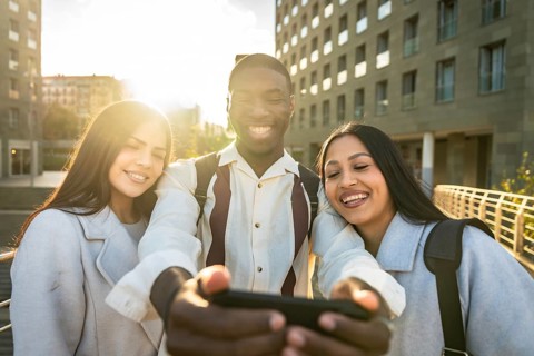 Group of diverse young adults smiling and having fun together while taking a selfie with a