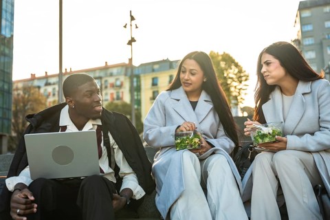 Diverse business colleagues enjoying a relaxed lunch break outdoors in the city, sitting on steps,