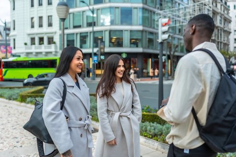Young multiracial friends meeting on an urban street, engaging in a pleasant conversation,