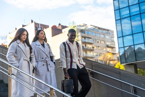 Three diverse business colleagues descending outdoor stairs, walking together after work or during