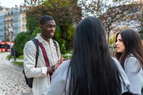 Young multiracial friends animatedly discussing ideas and stories on a city street, sharing