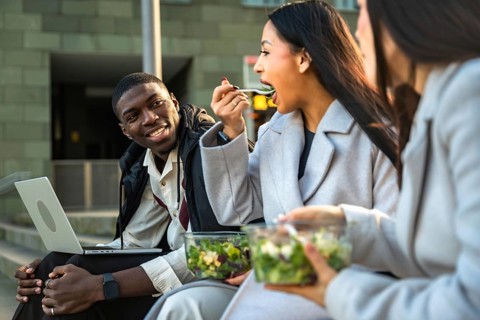 Multi ethnic young professionals enjoying a healthy salad for lunch during a break, sitting