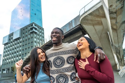 Cheerful diverse group of young adults standing closely together, smiling, laughing, and enjoying a