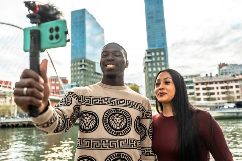 Smiling diverse couple creating content for social media, capturing a selfie video with a