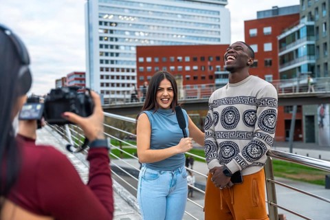 Camerawoman filming an interview with a female reporter holding a microphone and a young cheerful
