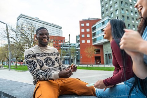 Group of diverse young adult friends laughing, smiling, and enjoying a casual urban leisure moment