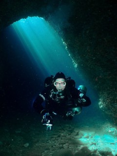 In an underwater cave, a diver moves through bright blue light. Fraskeric dive site, Stoja, Pula,