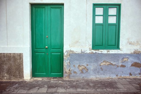 Landscape close-up of a green door and window in Arrecife, Lanzarote. Speckled plaster gives the