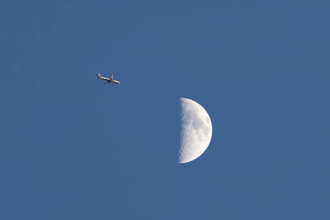 Airbus commercial passenger airliner jet aircraft of British airways in flight with the moon in the