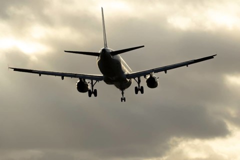 Commercial passenger airliner jet aircraft in flight on approach to land at sunset at London