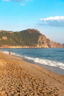 A couple walk along an empty Cleopatra Beach at sunset in the Turkish holiday resort town of Alanya