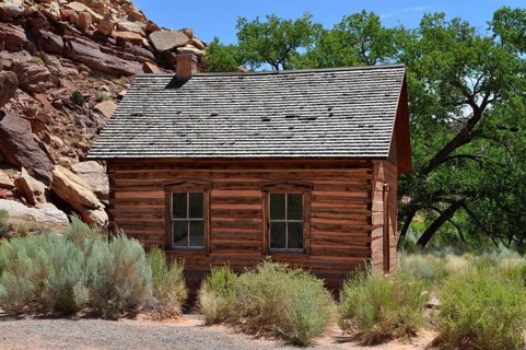 An old wooden cabin, old schoolhouse, between trees in a dry, summer landscape, Fruita, Capitol