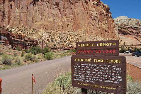 Information sign about possible flash flood hazards in a rocky canyon under clear skies, Capitol