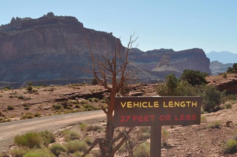Desert landscape with vehicle length road sign and rocky mountain range in the background, Capitol