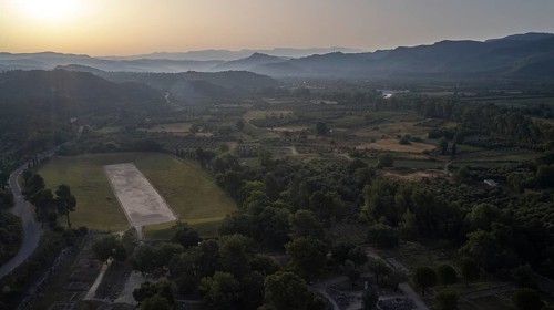 Ancient stadium in the morning backlight, wide landscape at sunset with hills and a large