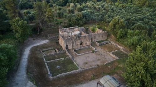 Building below Leonidaion, stone ruins of an ancient building surrounded by trees and paths, drone