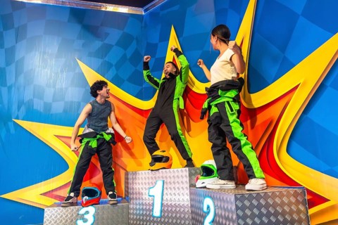 Joyful friends celebrating success on a racing podium, with the winner raising arms in triumph,