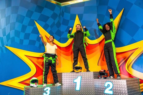 Three young multi ethnic adults celebrating their success, standing on a numbered podium wearing