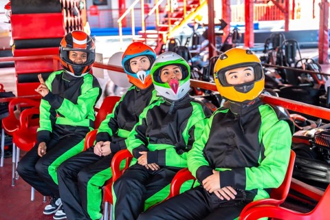 Group of young diverse adults wearing race suits and helmets, sitting on chairs and anticipating a
