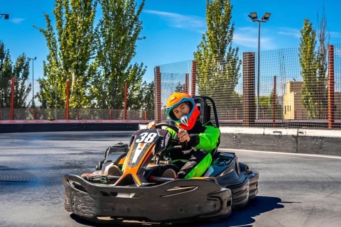 Young man in helmet and racing suit zooming a go kart on an outdoor asphalt track, enjoying speed