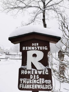 Snowy sign of the Rennsteig in wintry rural surroundings, hiking in the Franconian Forest nature